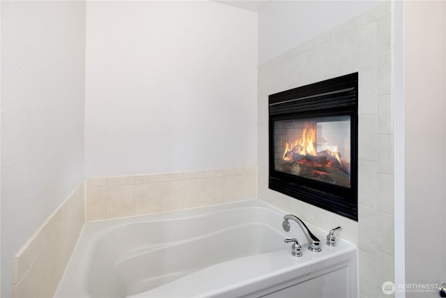bathroom with a tile fireplace and a bath