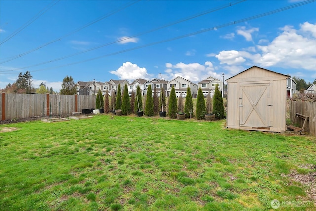 view of yard with a storage unit, a residential view, a fenced backyard, and an outbuilding