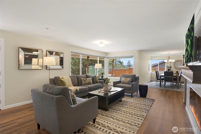 living area featuring a notable chandelier, baseboards, and wood finished floors
