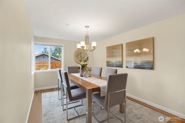 dining room featuring baseboards, wood finished floors, and a chandelier