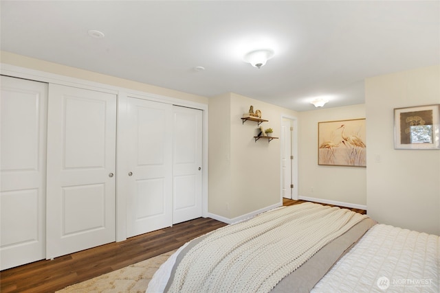 bedroom with baseboards, wood finished floors, and two closets