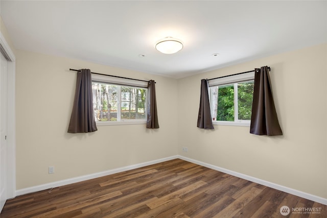 unfurnished room with baseboards and dark wood finished floors