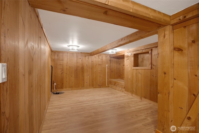 finished below grade area with light wood finished floors, baseboards, and wooden walls
