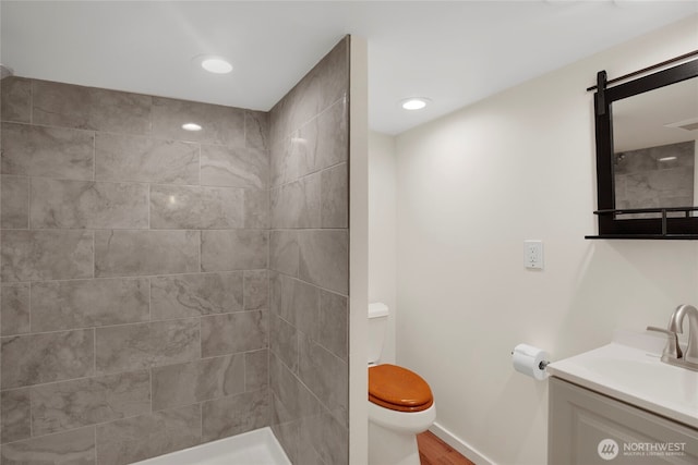 bathroom with a tile shower, recessed lighting, toilet, and vanity