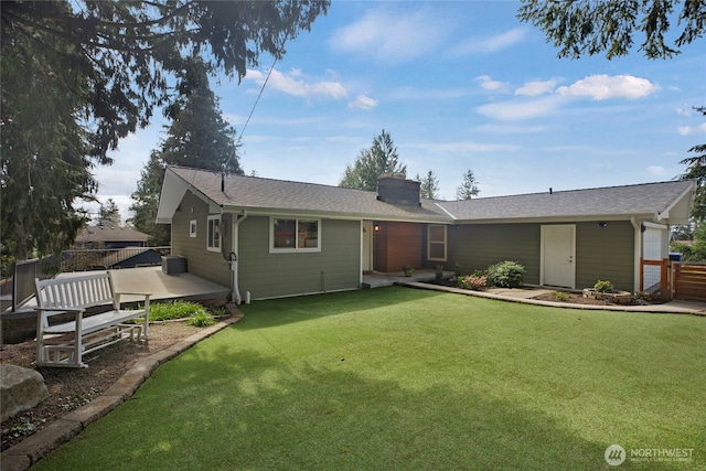 single story home featuring fence, a chimney, a garage, a deck, and a front lawn