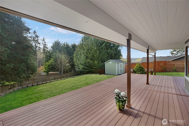 wooden terrace with an outdoor structure, a fenced backyard, a storage unit, and a yard