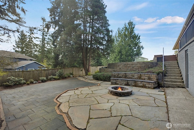 view of patio featuring an outdoor fire pit, a fenced backyard, and stairs