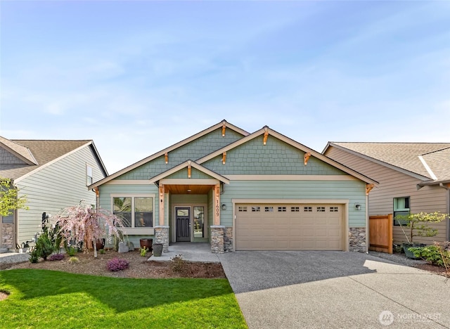craftsman house with an attached garage, driveway, a front yard, and stone siding