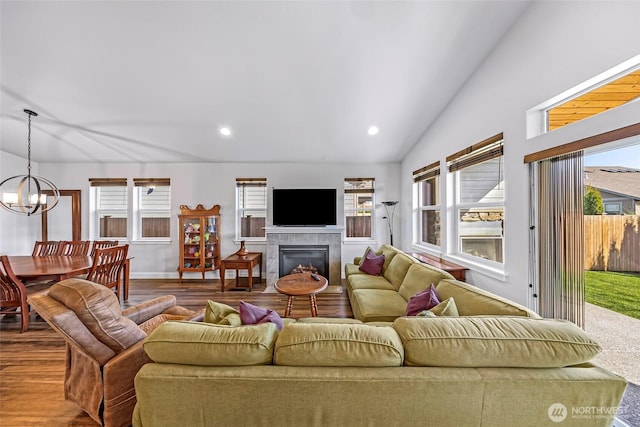 living room featuring a chandelier, a healthy amount of sunlight, wood finished floors, and lofted ceiling