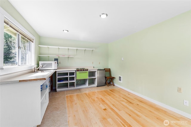 324 Gill Ln, Friday Harbor, WA 98250 - kitchen with visible vents, open shelves, freestanding refrigerator, light wood-type flooring, and white microwave