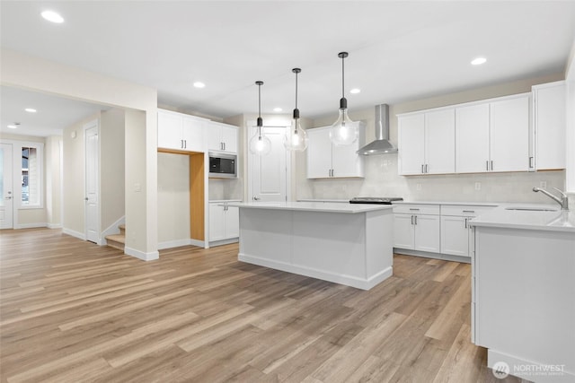 19457 116th St E, Bonney Lake, WA 98391 - kitchen with wall chimney range hood, stainless steel microwave, a sink, light wood-style floors, and a kitchen island