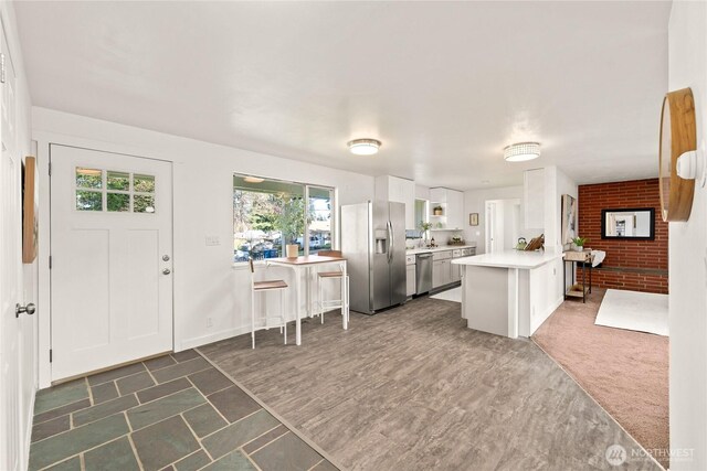 14207 6th Ave S, Burien, WA 98168 - kitchen featuring light countertops, a peninsula, dark wood finished floors, white cabinetry, and stainless steel appliances