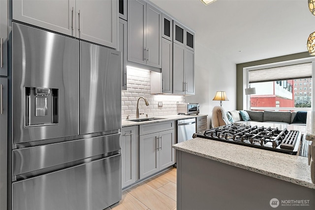 708 Market St Unit 711, Tacoma, WA 98402 - kitchen featuring gray cabinetry, backsplash, a sink, light stone countertops, and appliances with stainless steel finishes