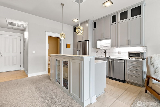 708 Market St Unit 711, Tacoma, WA 98402 - kitchen with gray cabinets, a kitchen island, stainless steel appliances, visible vents, and decorative backsplash