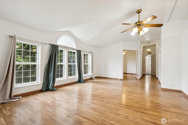 spare room featuring baseboards, light wood-style flooring, ceiling fan, and vaulted ceiling