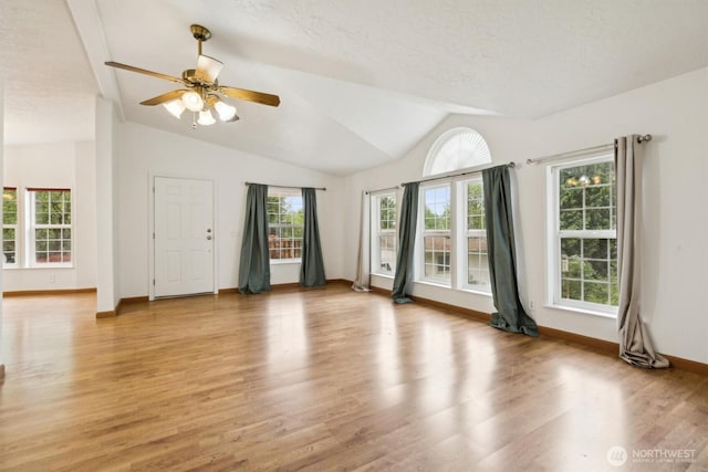 unfurnished living room featuring baseboards, light wood-style flooring, ceiling fan, and lofted ceiling