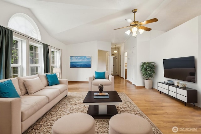 living area featuring a ceiling fan, baseboards, vaulted ceiling, and light wood-style floors