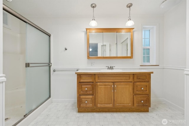 full bathroom with wainscoting, a stall shower, tile patterned floors, vanity, and a decorative wall