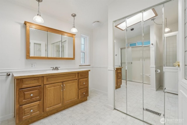 full bath featuring vanity, tile patterned floors, an enclosed shower, and a wainscoted wall