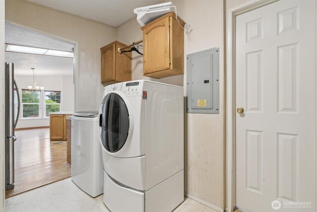 laundry room featuring electric panel, cabinet space, and a chandelier