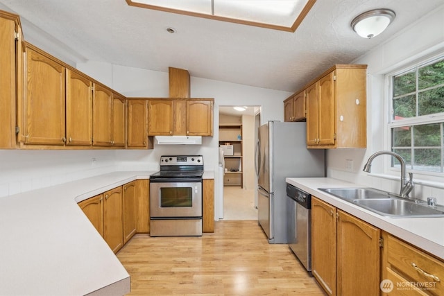 kitchen featuring lofted ceiling, light wood-style floors, under cabinet range hood, a sink, and stainless steel appliances