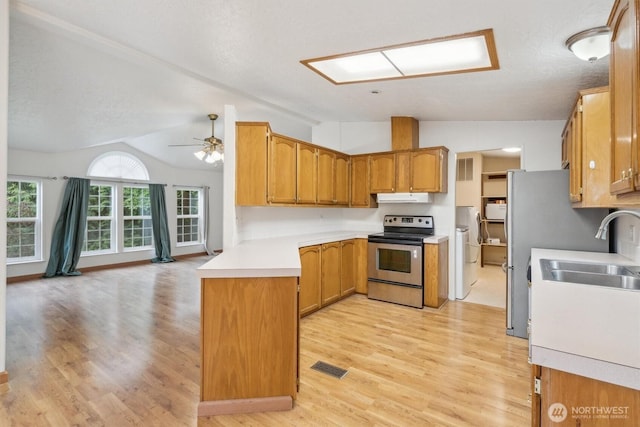 kitchen with stainless steel range with electric cooktop, a sink, light wood-style floors, light countertops, and vaulted ceiling