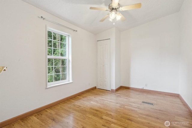 interior space featuring baseboards, visible vents, ceiling fan, and light wood-style floors