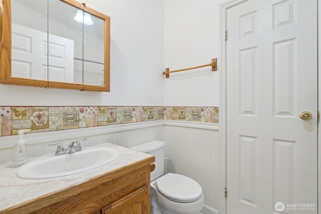 bathroom with vanity, wainscoting, and toilet