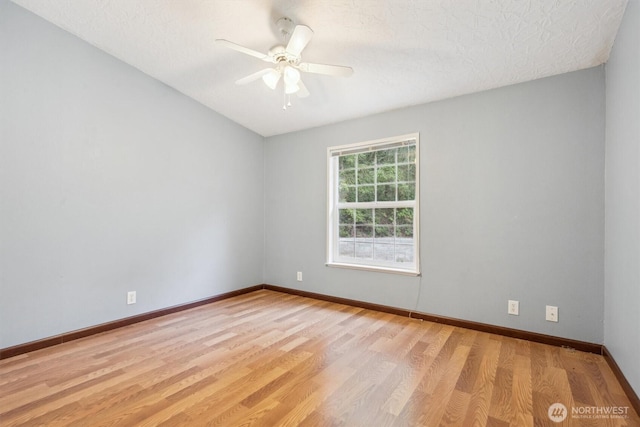 unfurnished room with ceiling fan, a textured ceiling, light wood-style flooring, baseboards, and lofted ceiling