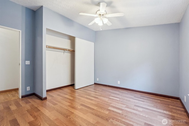 unfurnished bedroom featuring a closet, a ceiling fan, light wood finished floors, and baseboards