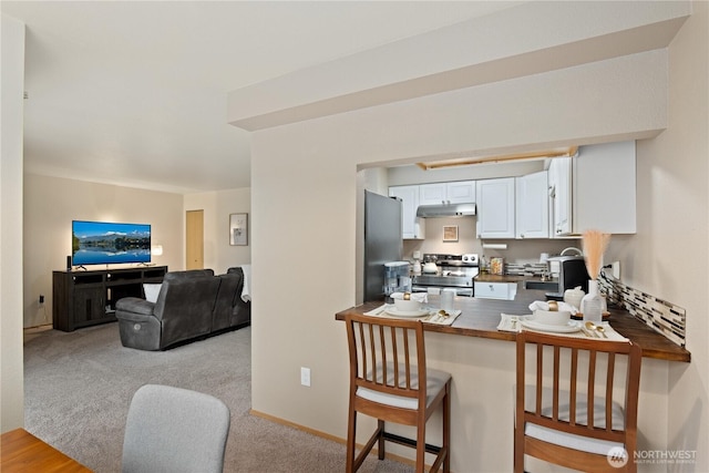18200 73rd Ave NE Unit B103, Kenmore, WA 98028 - kitchen with white cabinetry, light colored carpet, under cabinet range hood, dark countertops, and appliances with stainless steel finishes