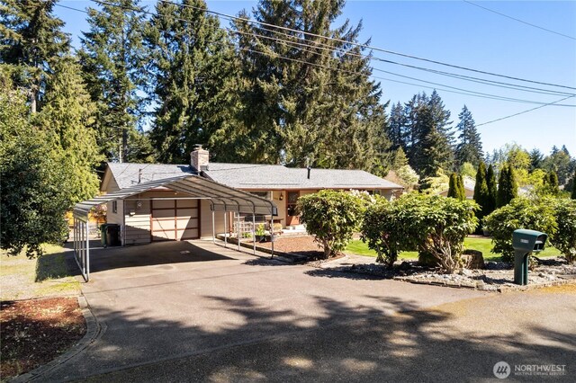 view of front of property featuring an attached garage, driveway, a chimney, and a carport