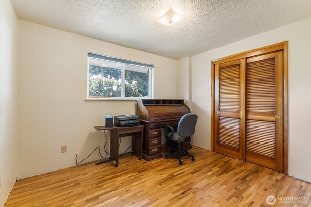 office area with light wood finished floors and a textured ceiling