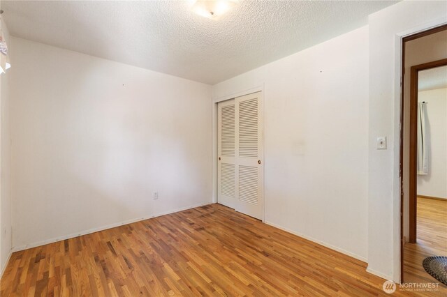 unfurnished bedroom with baseboards, light wood-style flooring, and a closet