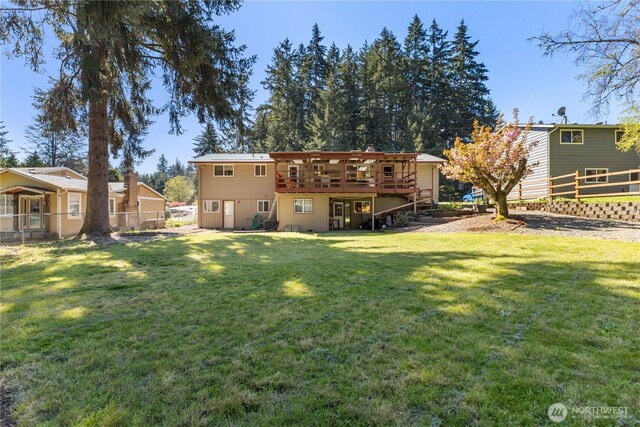 rear view of house featuring fence, a yard, and a deck