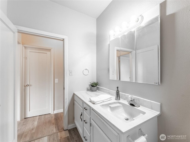 bathroom featuring baseboards, wood finished floors, and vanity