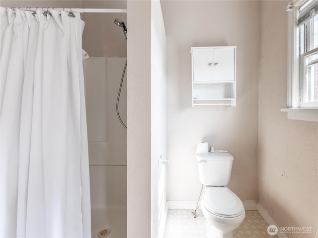 bathroom featuring toilet, a stall shower, baseboards, and tile patterned floors
