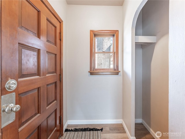 doorway featuring baseboards, wood finished floors, and arched walkways