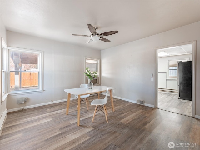 dining room featuring wood finished floors, a healthy amount of sunlight, and visible vents