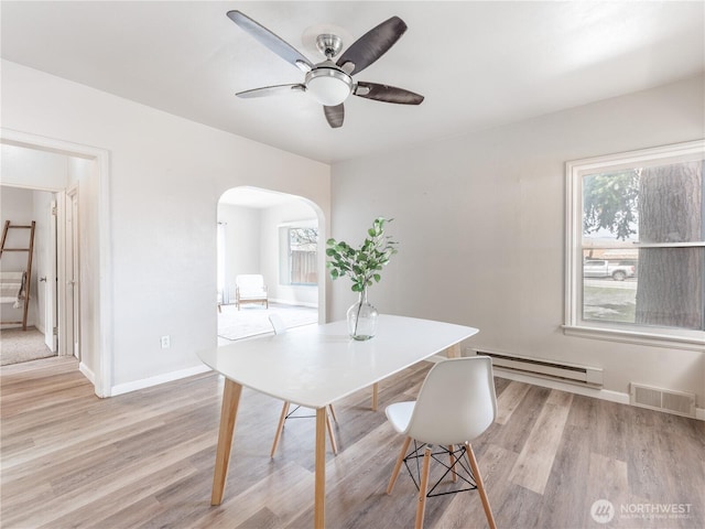 dining room featuring a baseboard radiator, a wealth of natural light, arched walkways, and visible vents