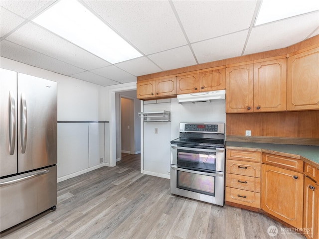 kitchen with under cabinet range hood, a drop ceiling, stainless steel appliances, and light wood-style floors