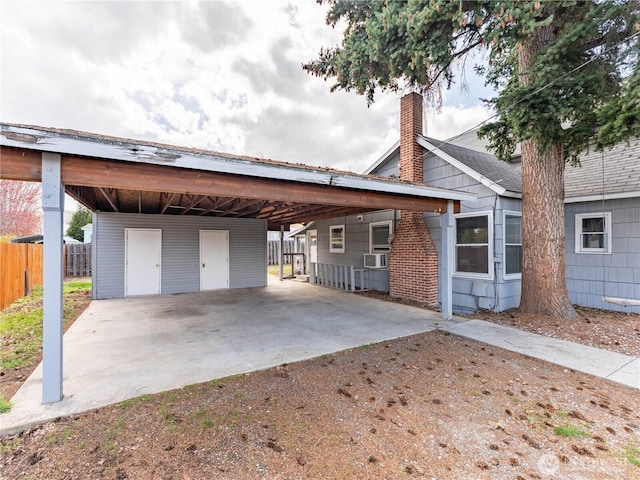 view of front of home featuring a chimney, cooling unit, fence, a carport, and dirt driveway