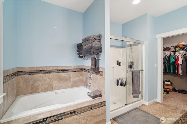 bathroom featuring a shower stall, a bath, and a walk in closet