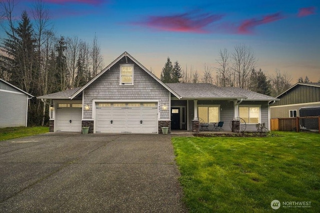 view of front of house featuring driveway, stone siding, and a yard