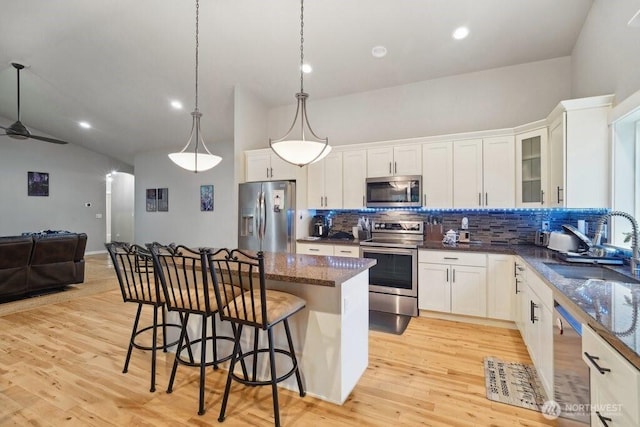 kitchen featuring a sink, a breakfast bar, appliances with stainless steel finishes, a center island, and open floor plan