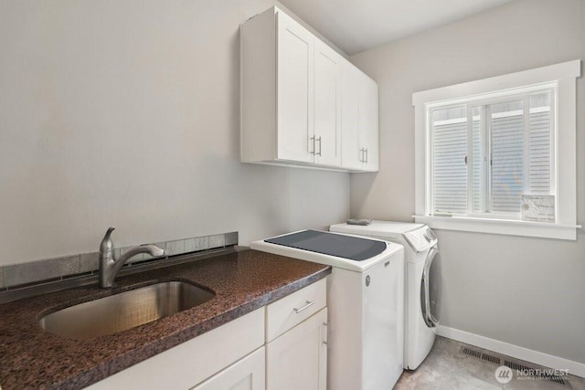 washroom with visible vents, baseboards, a sink, cabinet space, and separate washer and dryer