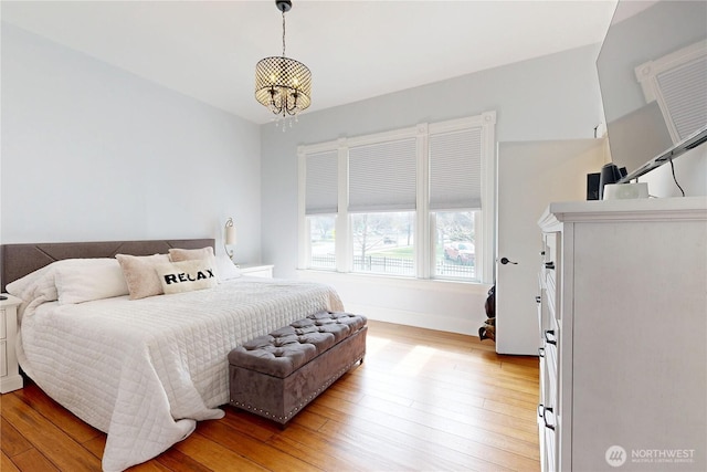 bedroom featuring a chandelier, light wood-style floors, and baseboards