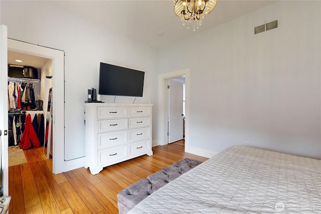 bedroom featuring visible vents, a closet, a notable chandelier, a spacious closet, and light wood-style flooring