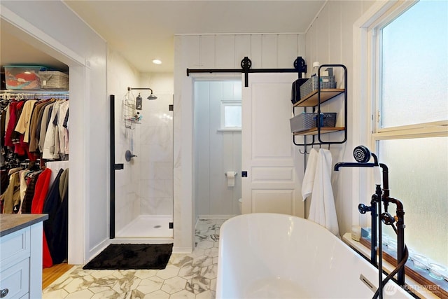full bathroom with a shower stall, a freestanding tub, vanity, and a spacious closet