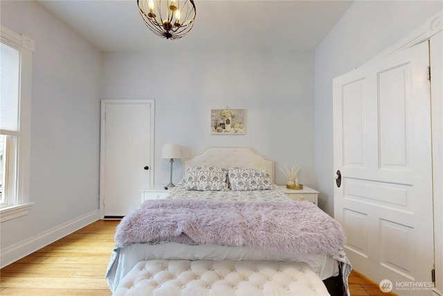 bedroom featuring a chandelier, baseboards, and wood finished floors